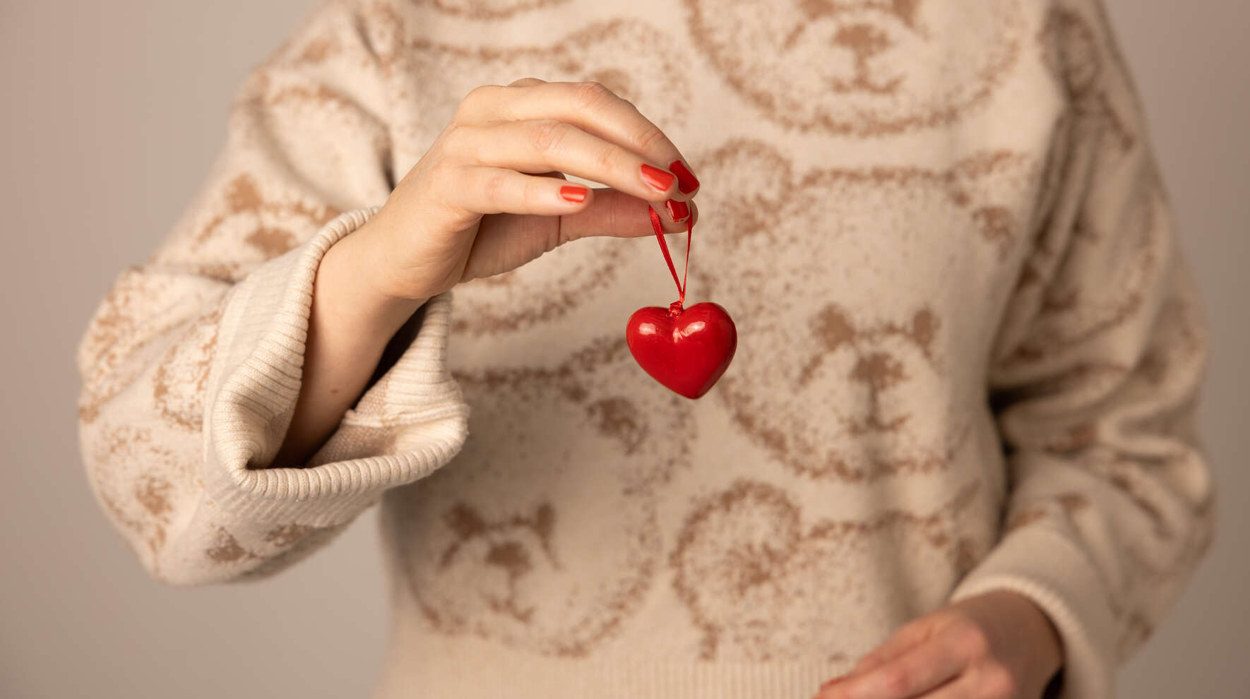 Nainen pitelee punaista muovista sydäntä edessään.